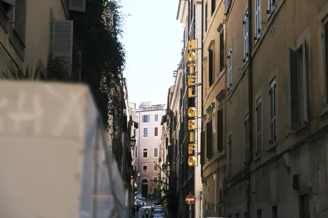 A narrow street in Monti with a tall yellow Hotel Grifo sign.