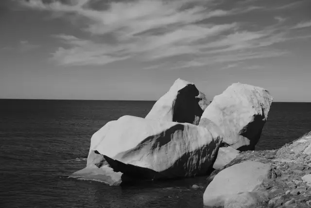 Large white tuff boulders at the water's edge under streaky clouds.