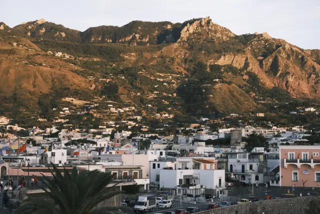 The town of Forio below Monte Epomeo, the mountain lit orange at sunset.