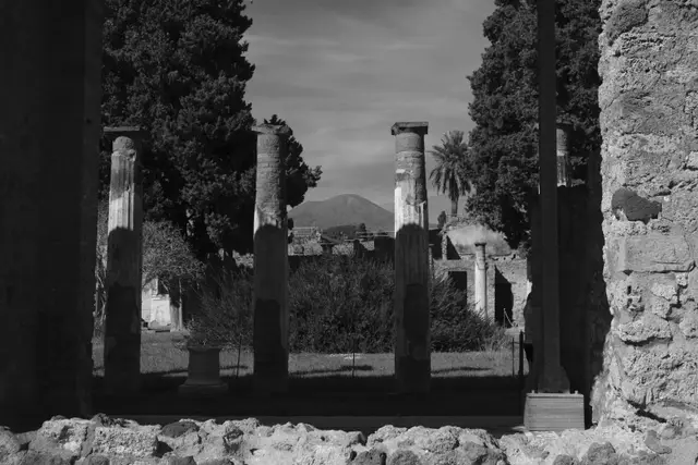 Broken columns of a Pompeii house with Vesuvius between them.