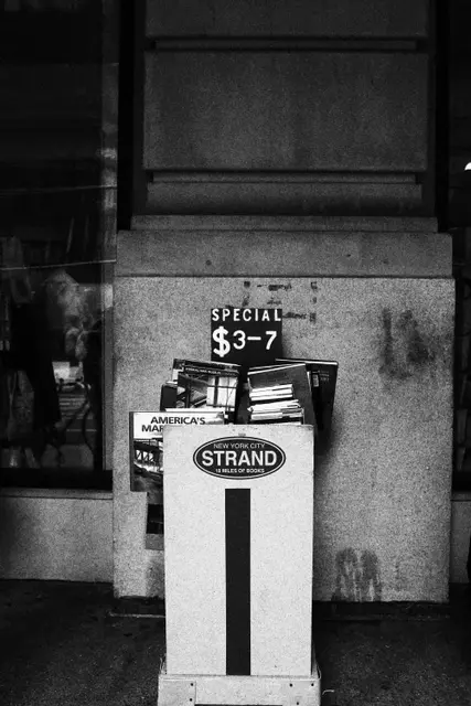 Black and white: a Strand book cart by a column, a sign reading Special $3–7.