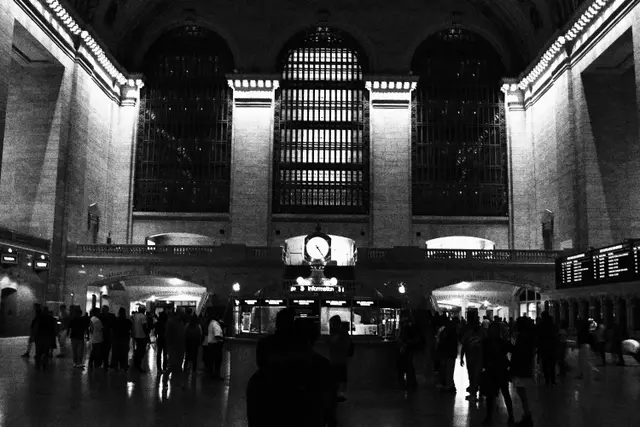 Black and white: the main concourse of Grand Central Terminal, its tall arched windows above the crowd and the clock.