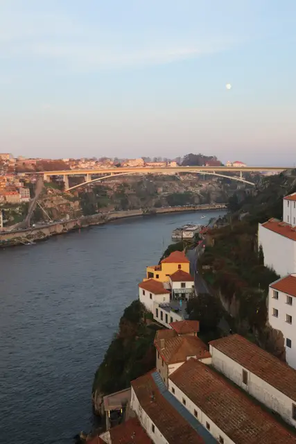 The Douro winding between steep banks at dusk, a bridge spanning it and the moon in a pink sky.